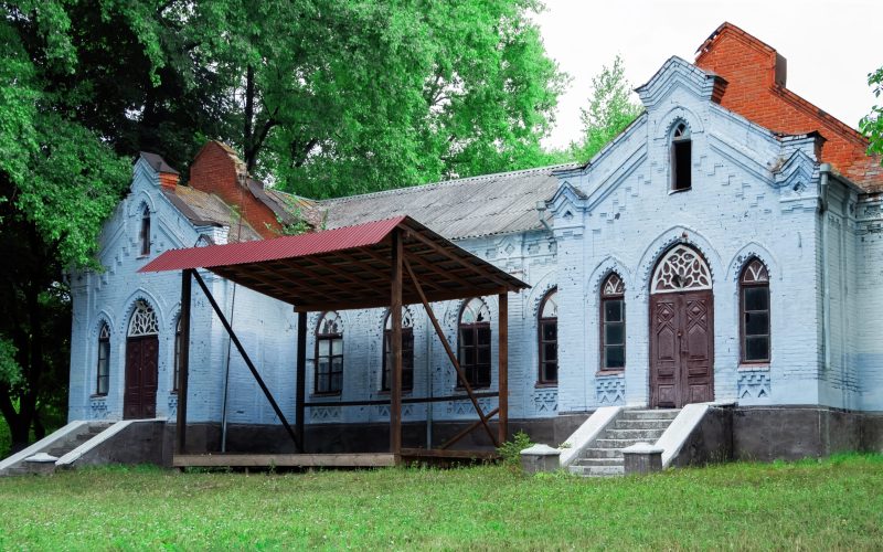 Abandoned old rural house in Moldova with blue facade, greenery near it in Moldova